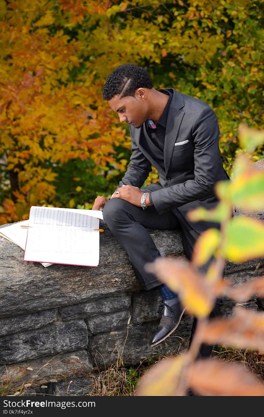 Man Wearing Black Suit Reading Book