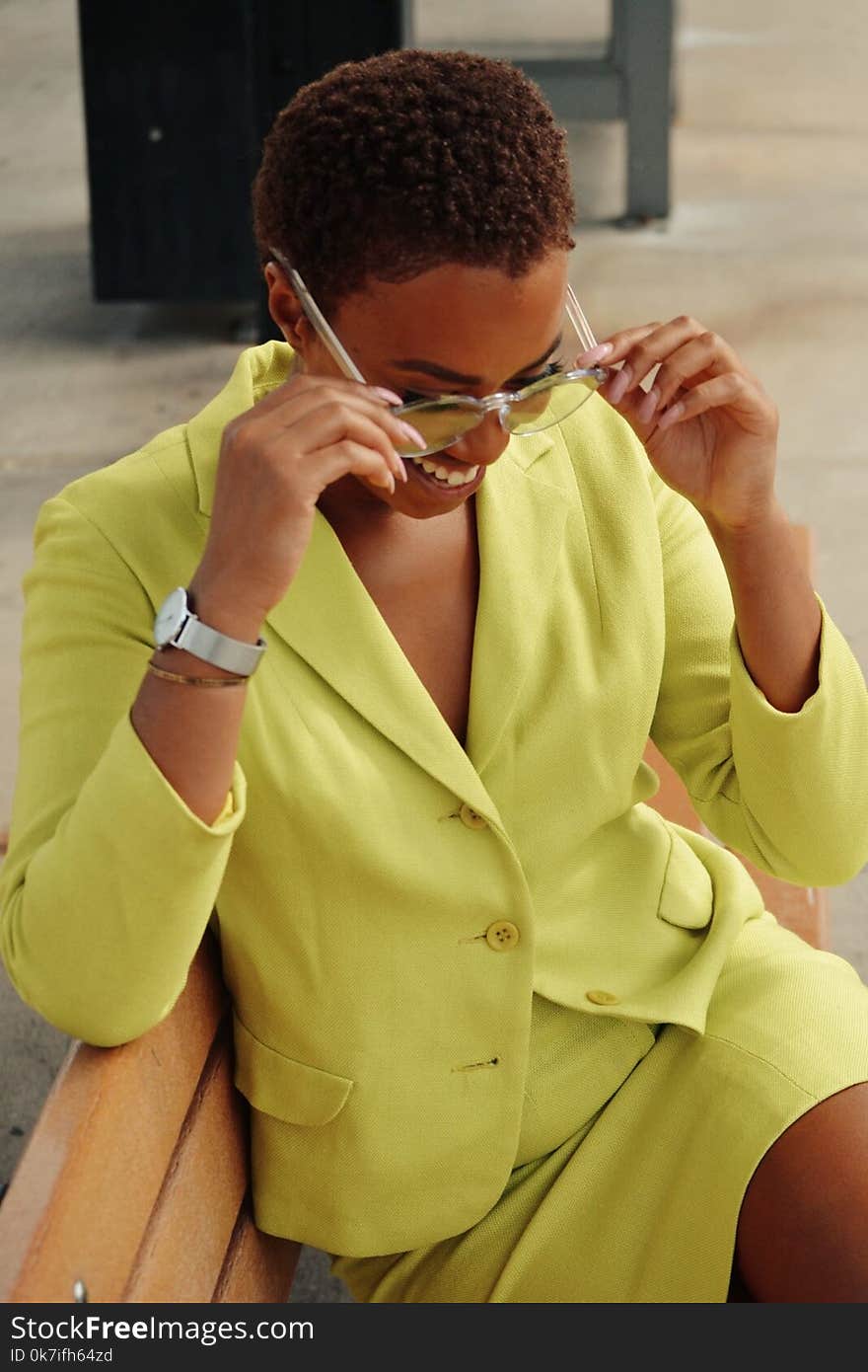 Woman Holding Sunglasses Sitting on Bench