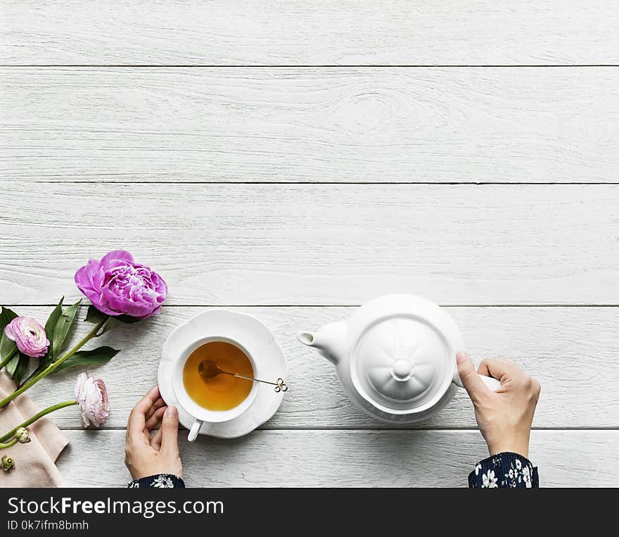 Person Holding White Ceramic Teapot on White Wooden Surface