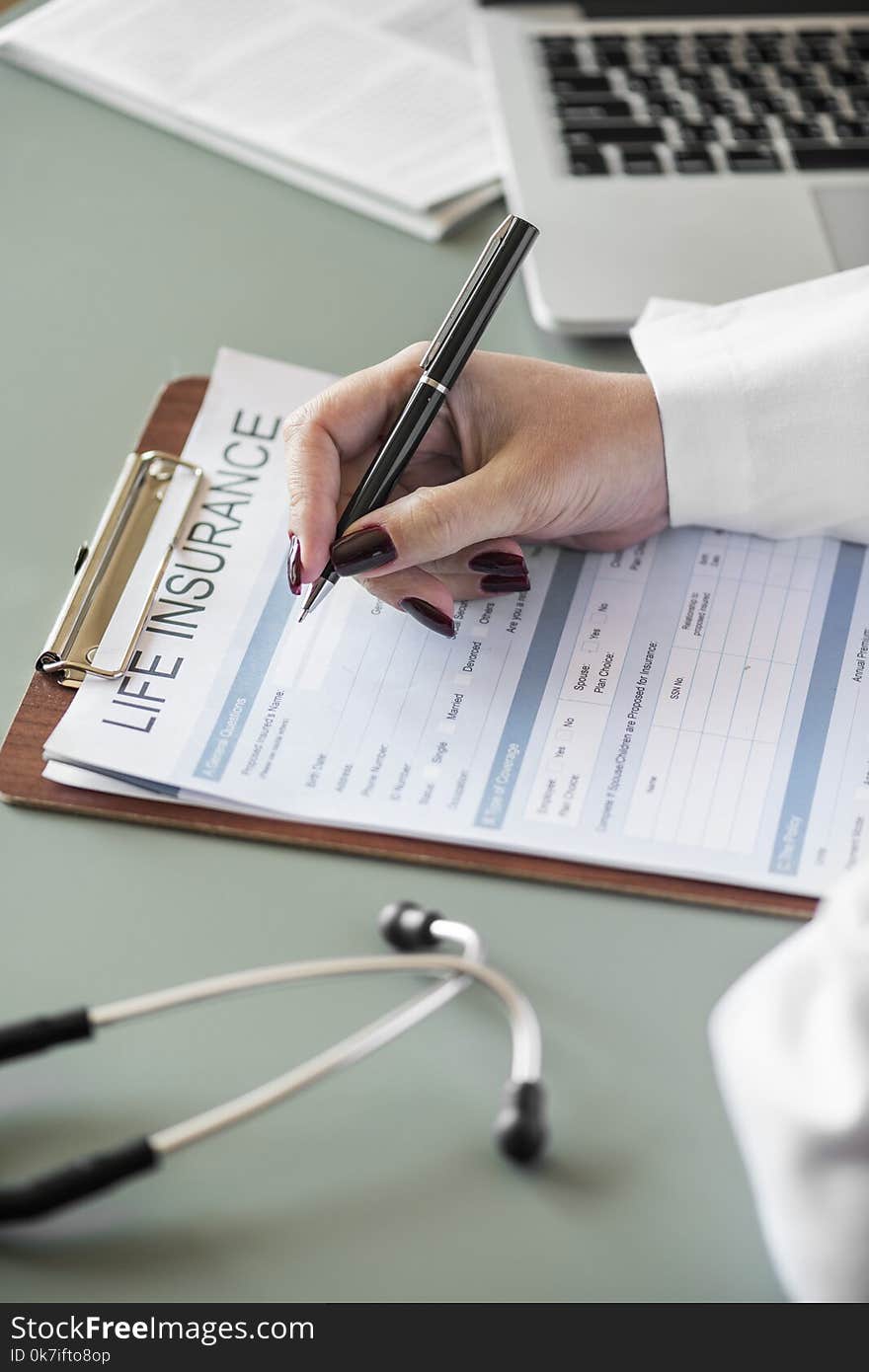 Person Holding Pen Writing on Life Insurance Paper