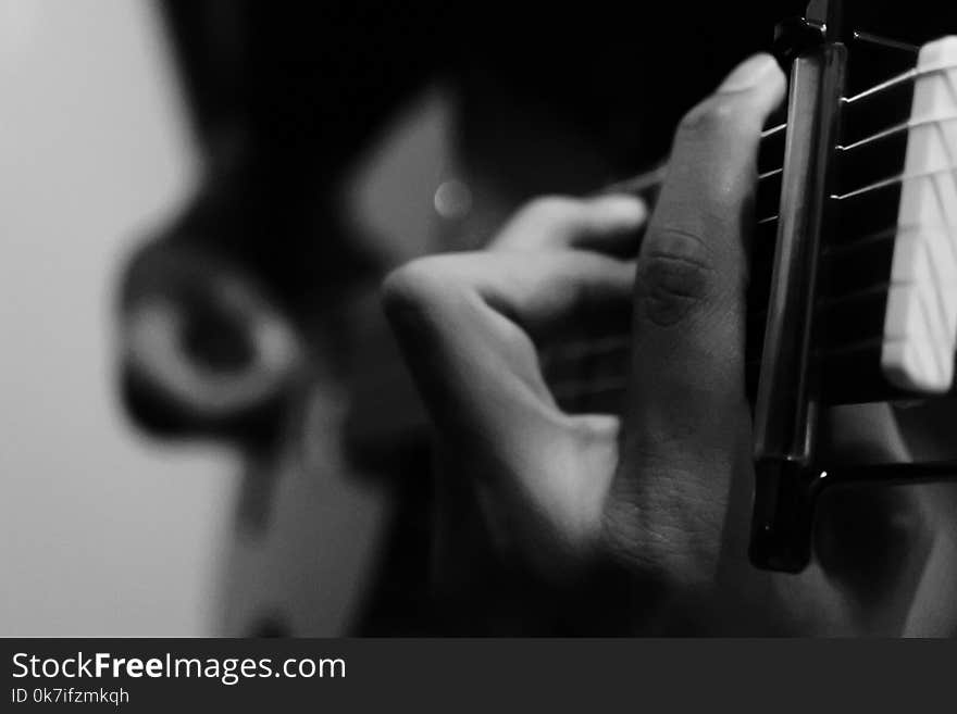 Person Holding Guitar in Grayscale Photography