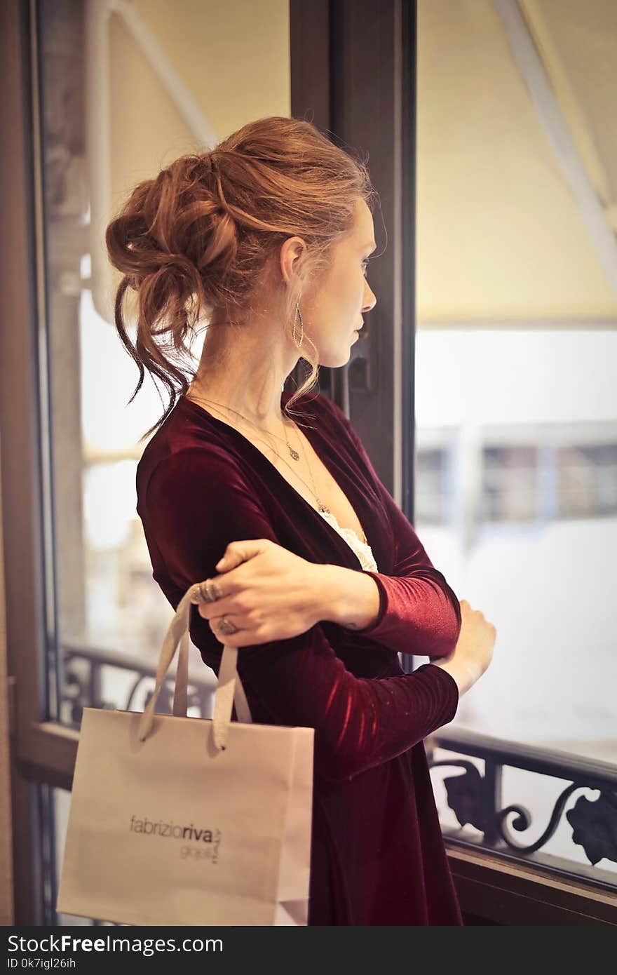 Woman Holding White Paper Bag While Looking at the Window