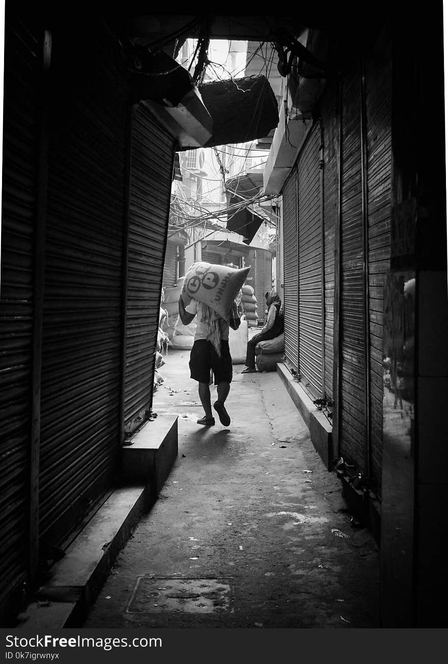 Grayscale Photo of Man Carrying Sack