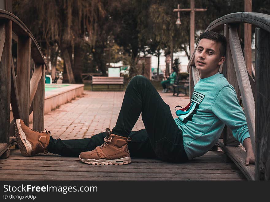 Man Sits on Wooden Bridge