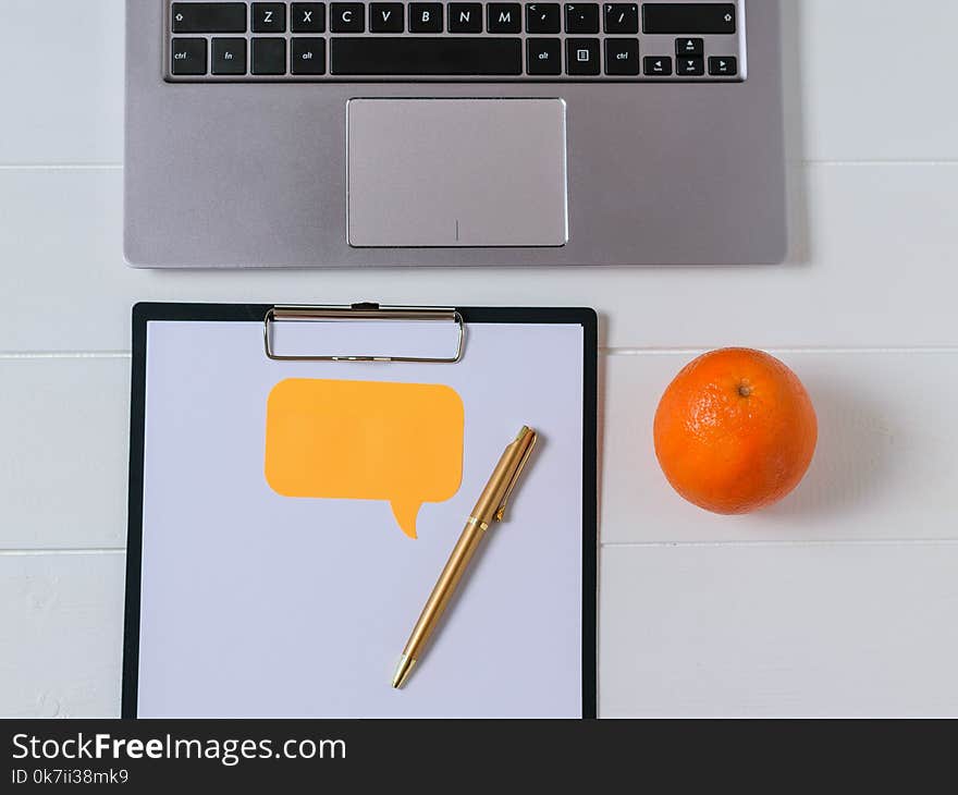 Place for text on tablet with paper, laptop and orange on white table. The concept of modern education. Place for text on tablet with paper, laptop and orange on white table. The concept of modern education.