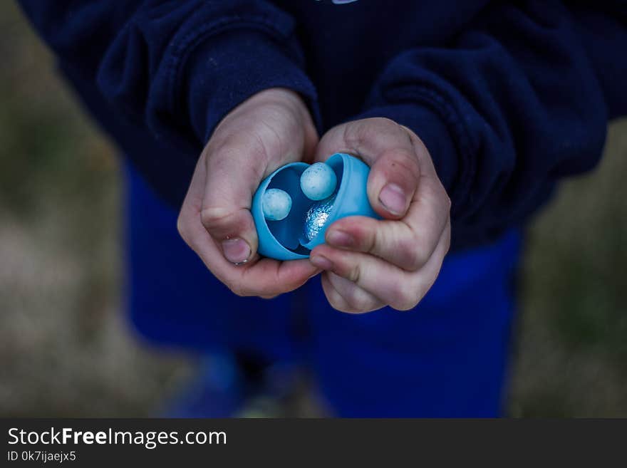 A child with dirty hands holding a blue Easter egg filled with treats. A child with dirty hands holding a blue Easter egg filled with treats