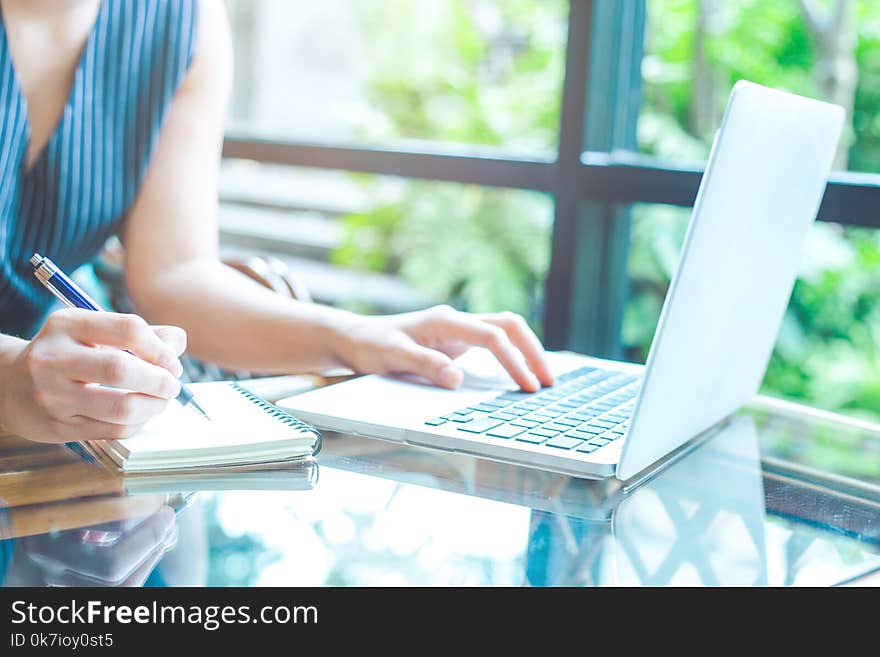 Business woman hand is writing on a notepad with a pen and using