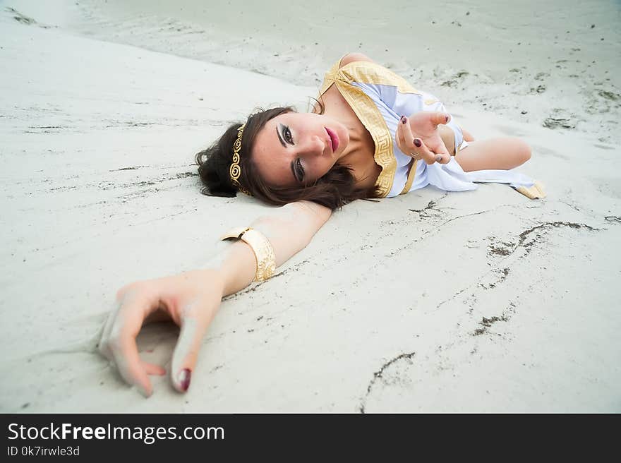 Young pretty woman in greek tunic on sand