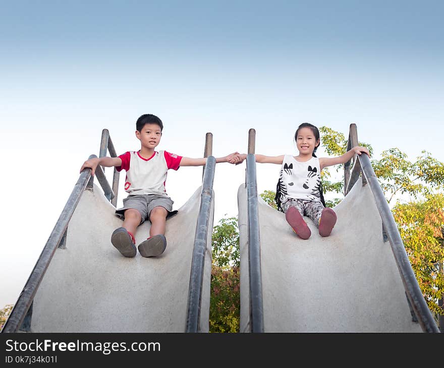 Asia pretty little girl and handsome boy play the slider in the garden