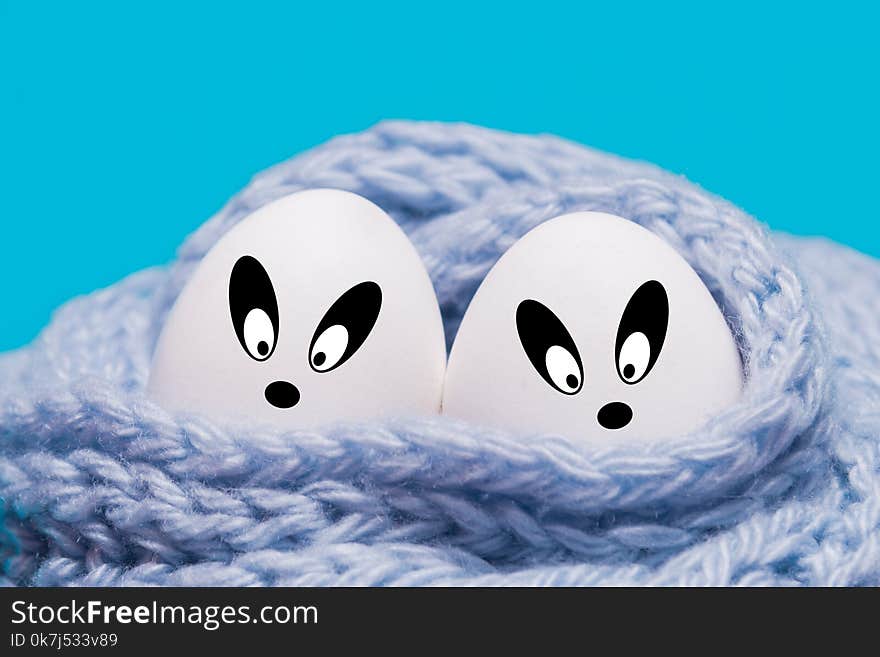 Two white eggs wrapped in a knitted scarf