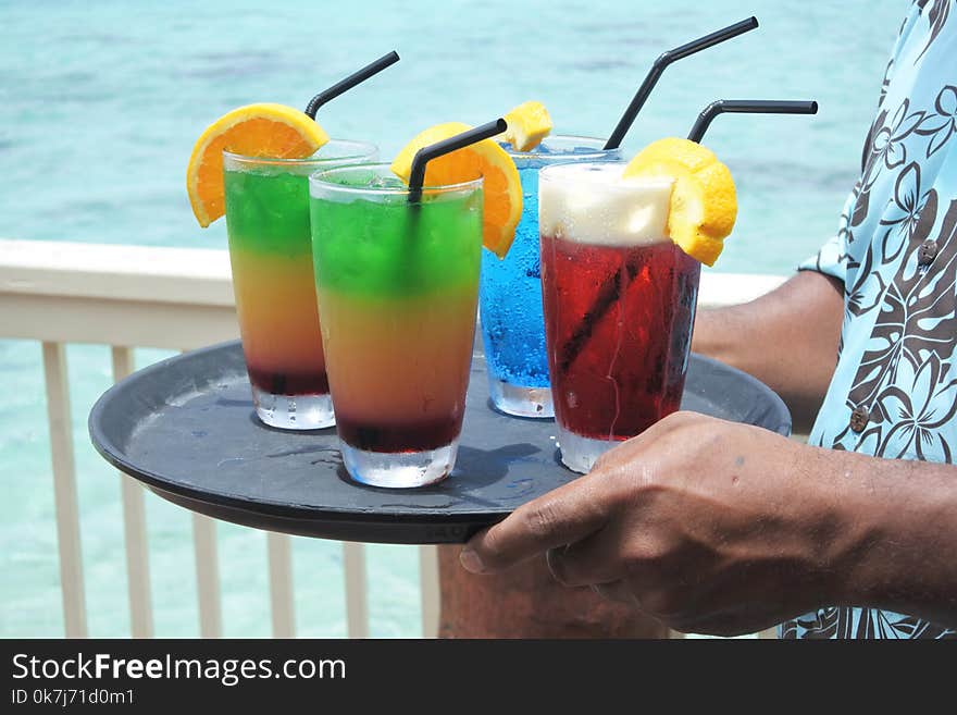 Pacific islander male waiter serving cocktails on a tropical pacific island resort in Rarotonga, Cook Islands. Drinks background. Copy space