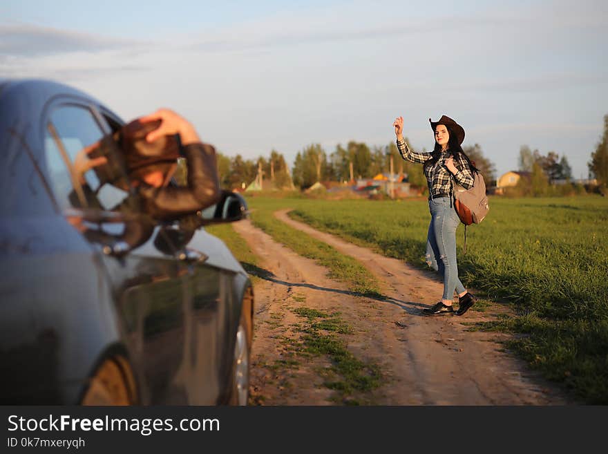 A girl in jeans and a hat travels the summer in the countryr. A girl in jeans and a hat travels the summer in the countryr