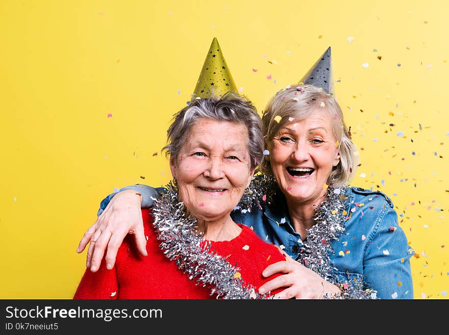 Portrait of a senior women in studio on a yellow background. Party concept. Close up.