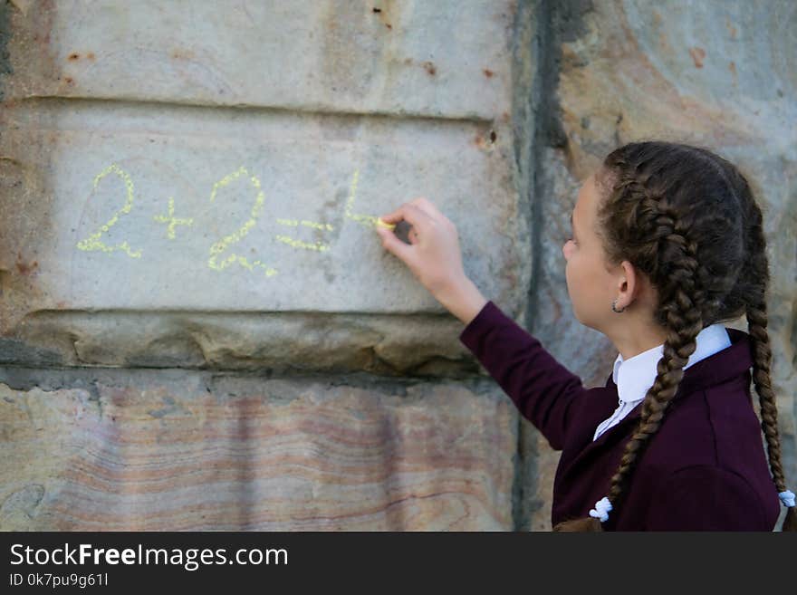 Girl With Pigtails, Wrote A Mathematical Example On A Stone Wall. Schoolgirl