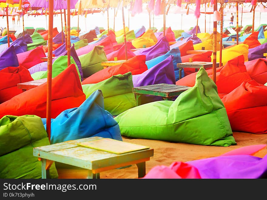 Multicolored bright beach umbrellas, ottomans and tables in the beach cafe. Summer multicolored background