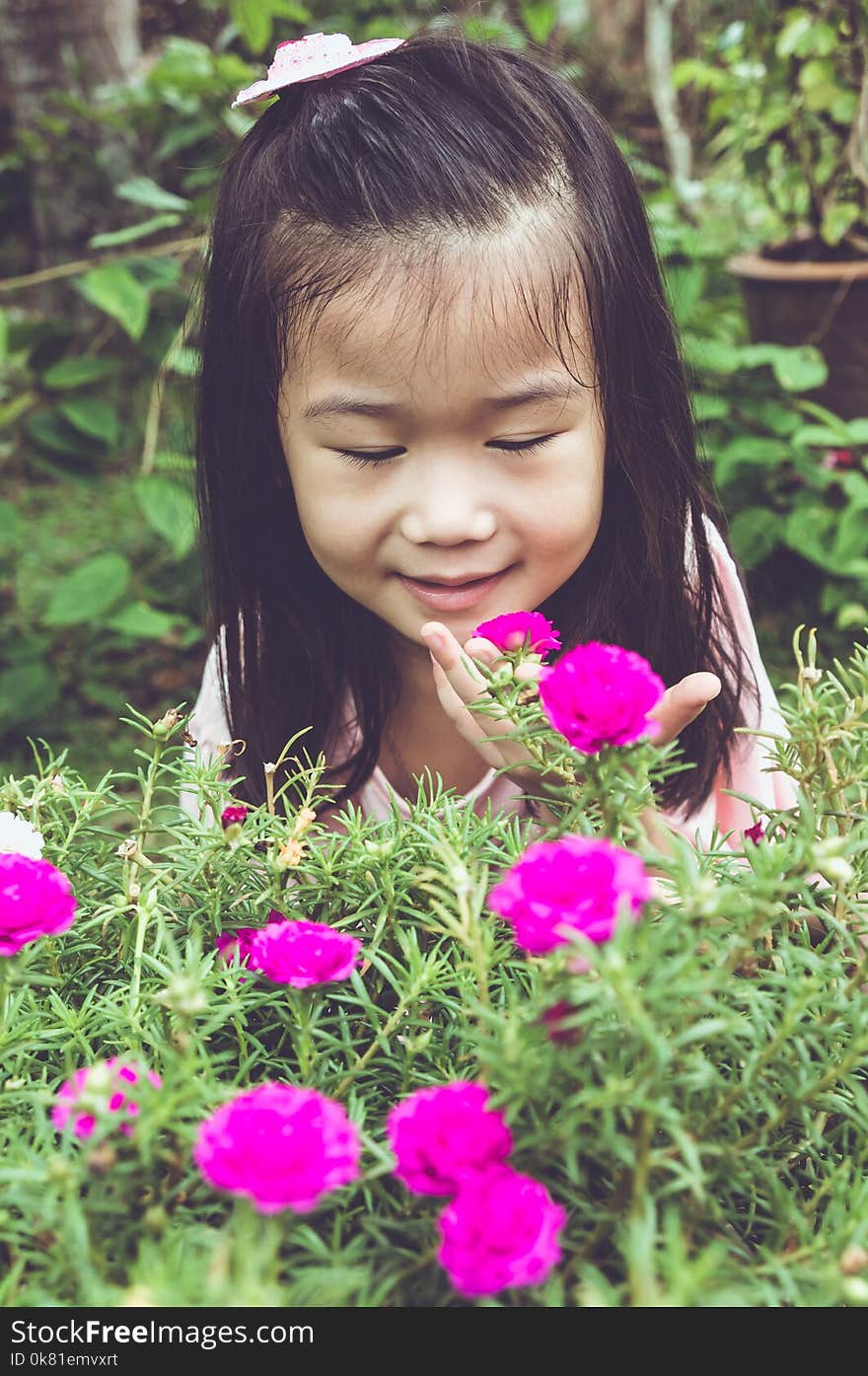 Asian child admiring for pink flowers and nature around at backyard. Vintage tone.