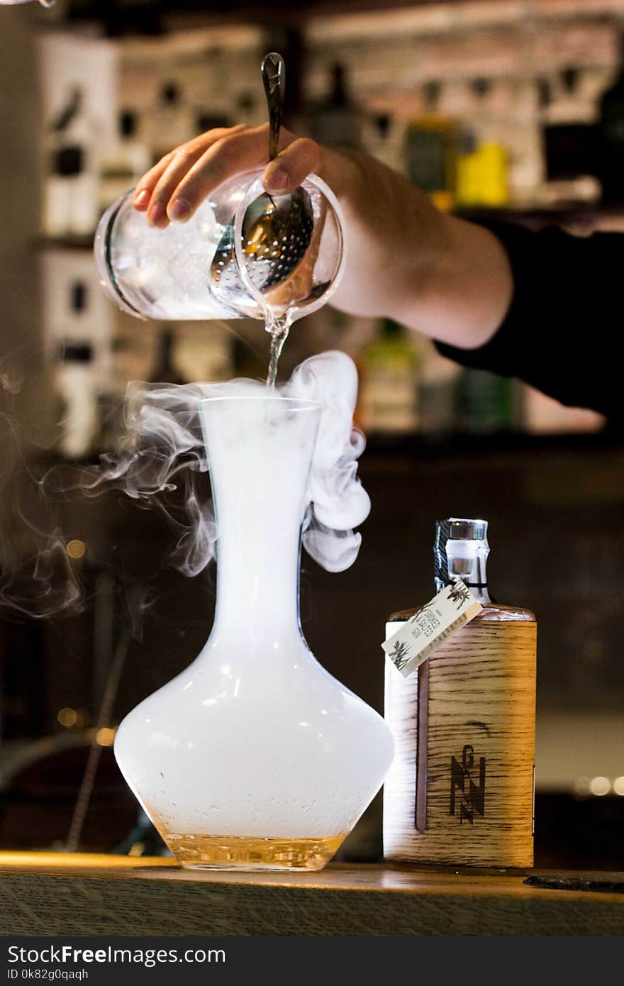 Person Pouring Liquid Into Smoking Glass Container