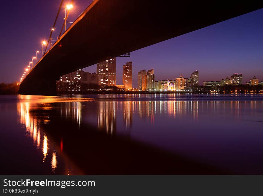 Night city. Beautiful glowing bridge over the river.