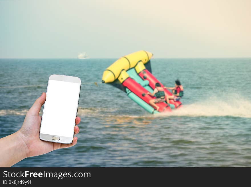 Hand holding mobile smart phone with blurry marine sport background.