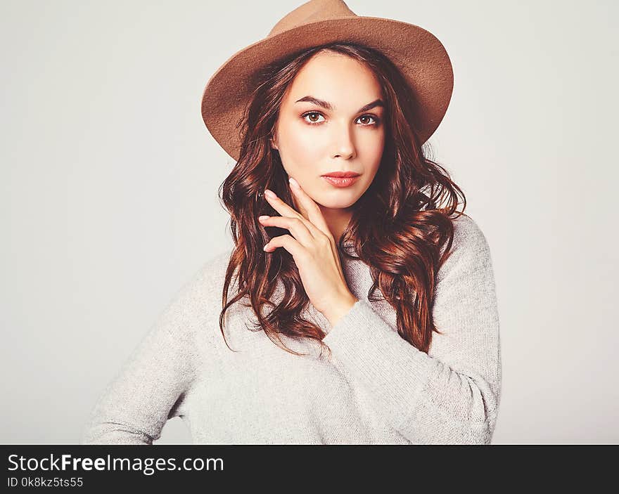 Portrait of young stylish laughing girl model in gray casual summer clothes in brown hat with natural makeup on gray background. Looking at camera. Portrait of young stylish laughing girl model in gray casual summer clothes in brown hat with natural makeup on gray background. Looking at camera