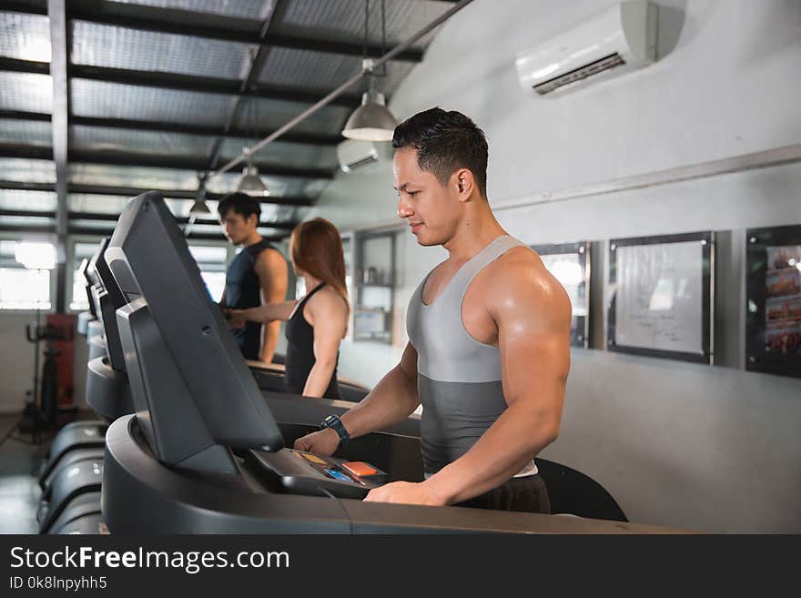 Healthy men start a treadmill together in a sport center. Healthy men start a treadmill together in a sport center