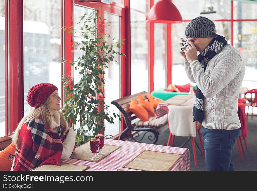 Young photographer with a girl in a cafe