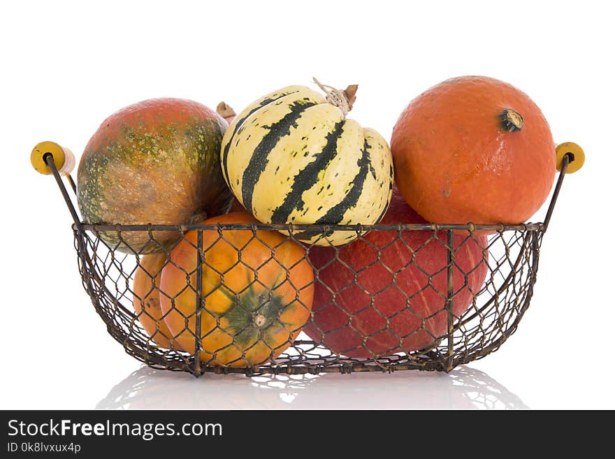 Orange and green pumpkins in vintage basket isolated over white background. Orange and green pumpkins in vintage basket isolated over white background