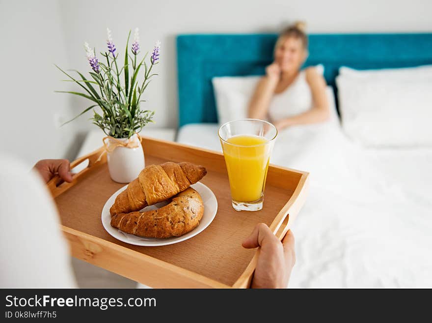 Man bringing breakfast to his girlfriend in bed