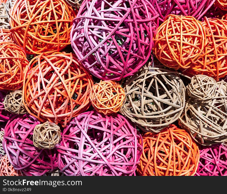 Balls of multicolored straw and thin branches illuminated by bright sunlight. The balls lie in a chaotic manner.