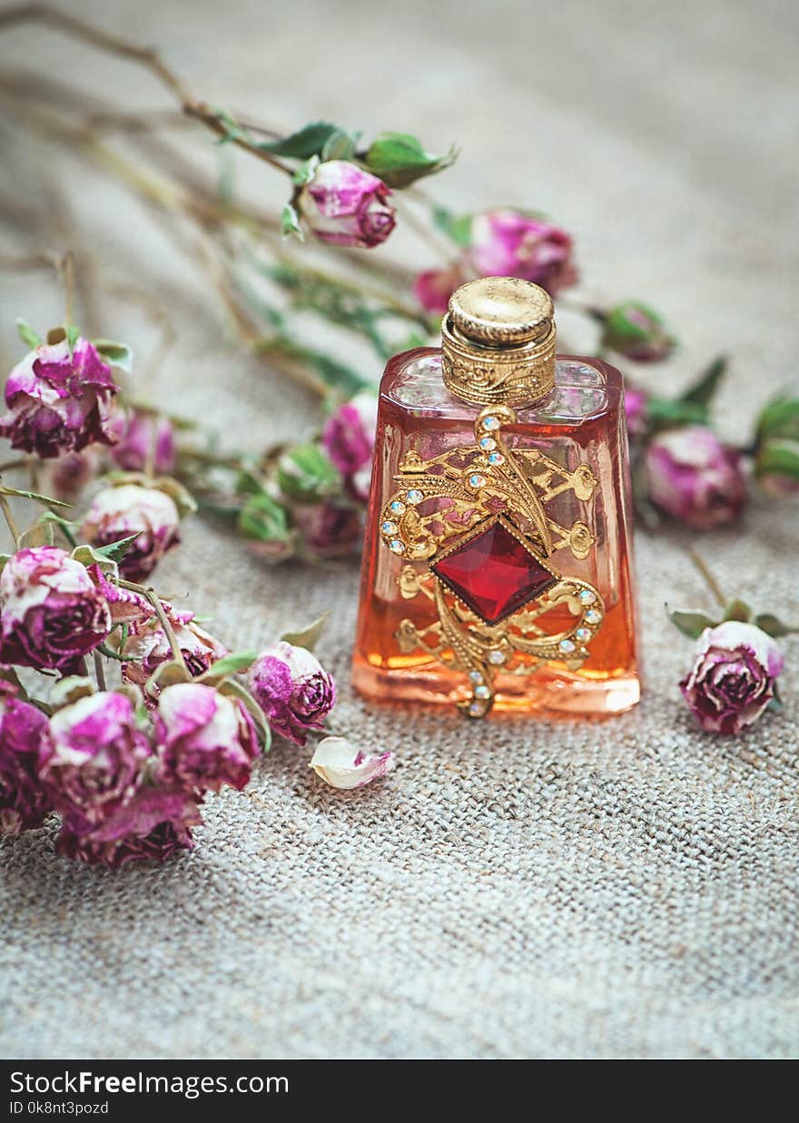 Dry tea roses and vintage perfume bottle on the sackcloth background