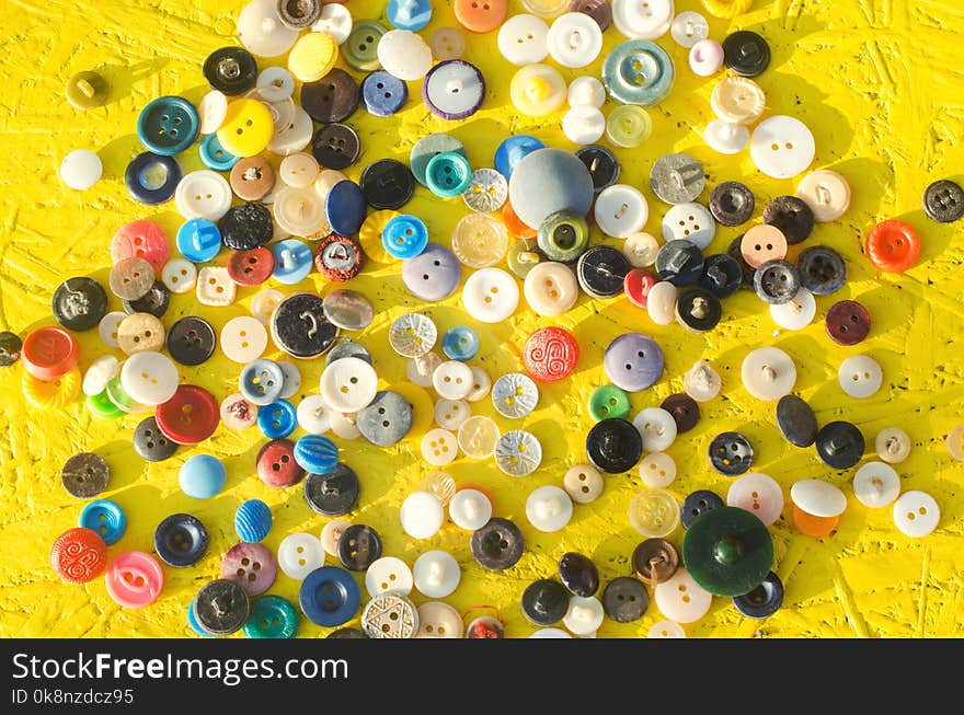 A set of buttons on a yellow background. needlework, hobby, creative, antiques.