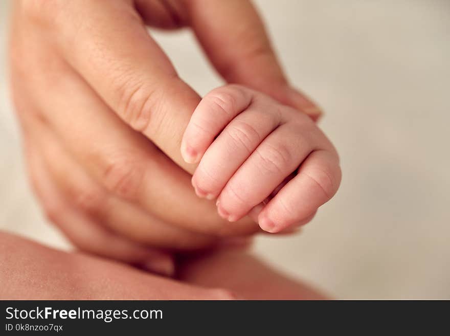 A newborn baby holds his mother`s hand