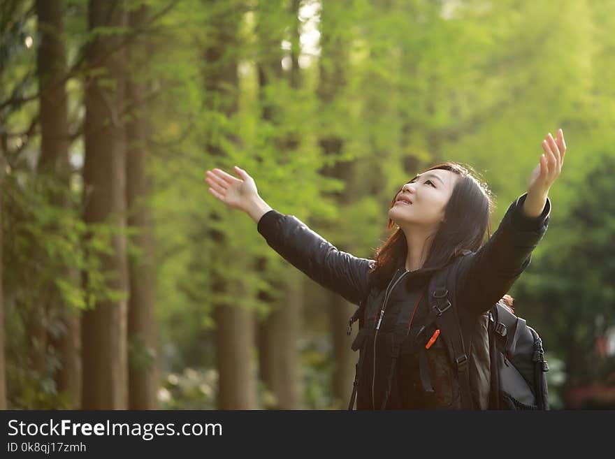 Freedom happy woman feeling alive and free in nature breathing clean and fresh air, carefree young adult dancing in forest or park showing happiness with arms raised up, spring allergies concept. Asian Chinese girl. peach blossom small apple flowering, Freedom happy woman feeling free in nature in spring summer outdoor, with flower in mounth, pink red colorful fun