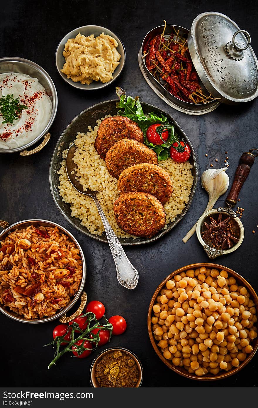Assorted jewish and middle east levante cuisine prepared traditional food in dishes and pans viewed from above served on dark table surface. Assorted jewish and middle east levante cuisine prepared traditional food in dishes and pans viewed from above served on dark table surface