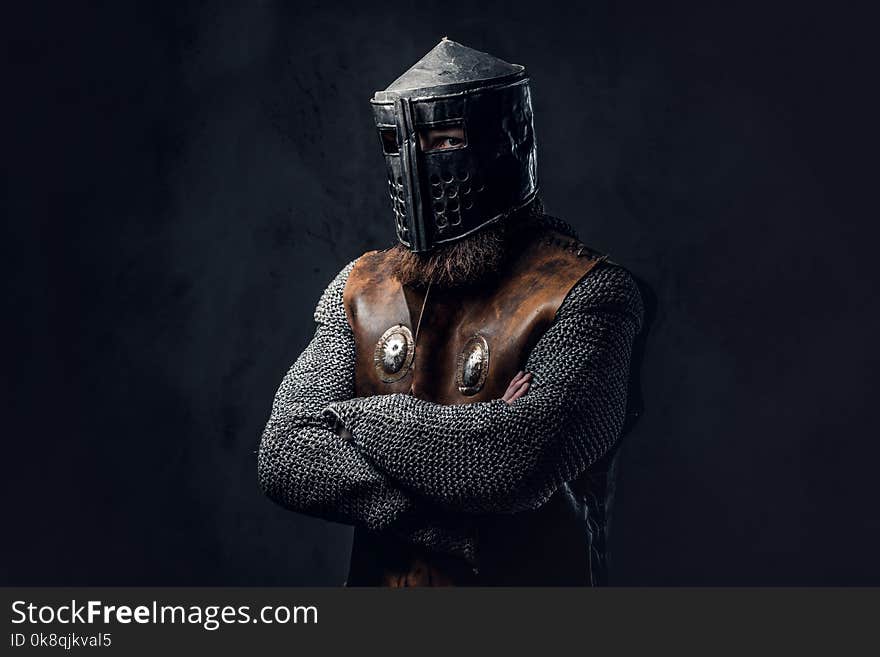 Studio portrait of a male Viking dressed in Nordic armor and an iron helmet over dark grey background. Studio portrait of a male Viking dressed in Nordic armor and an iron helmet over dark grey background.