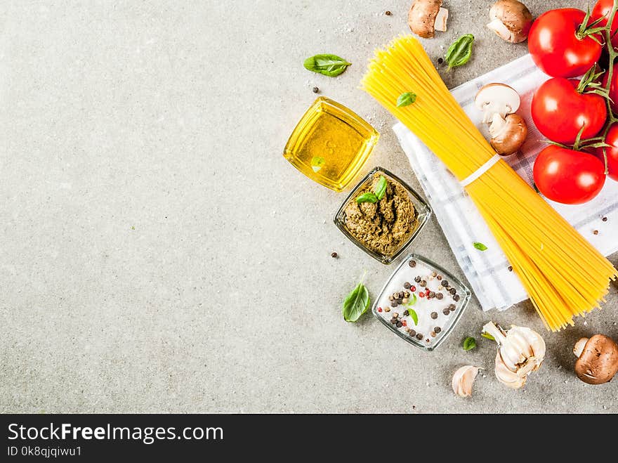 Food background, ingredients for cooking dinner. Pasta spaghetti, vegetables, sauces and spices, grey stone background copy space top view. Food background, ingredients for cooking dinner. Pasta spaghetti, vegetables, sauces and spices, grey stone background copy space top view