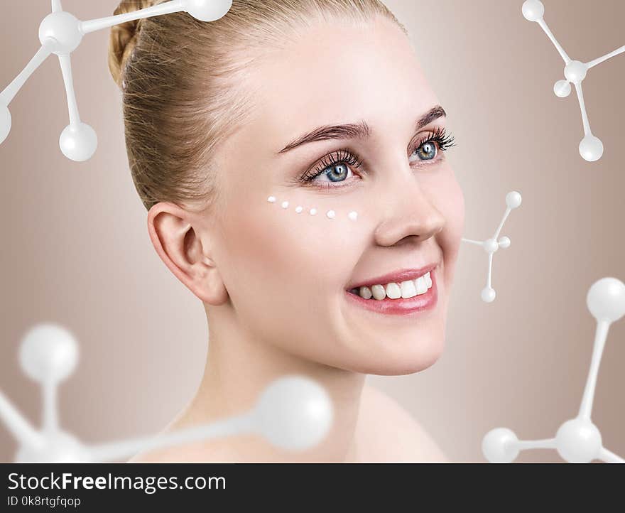 Young woman with cream dots among white molecules. Over beige background.