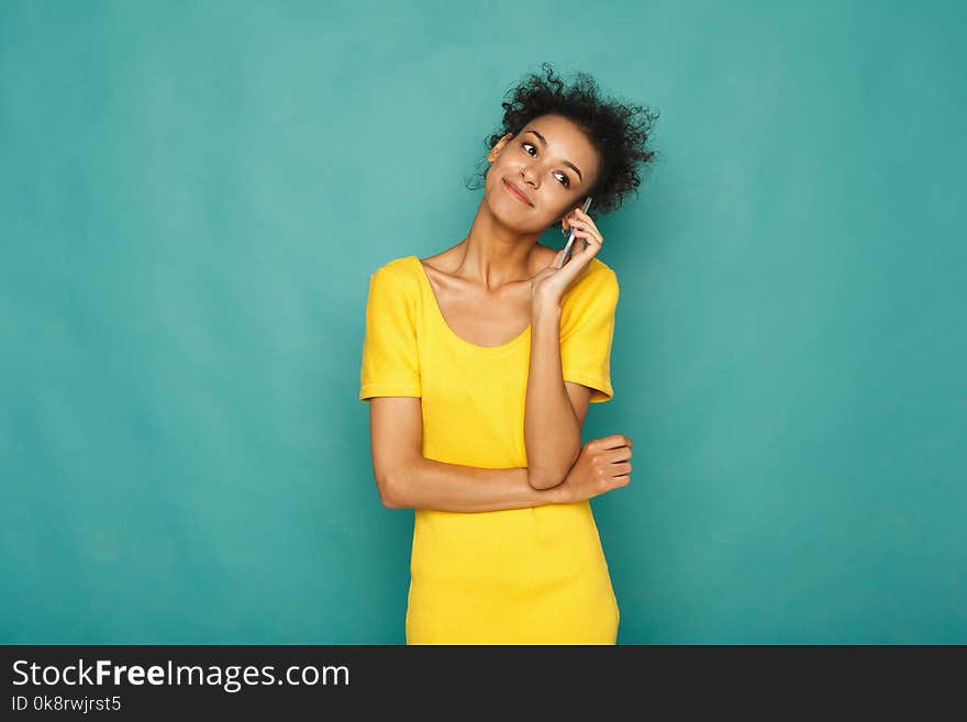 Modern lifestyle and communication. Smiling beautiful african-american woman talking on phone, at blue studio background, copy space. Modern lifestyle and communication. Smiling beautiful african-american woman talking on phone, at blue studio background, copy space