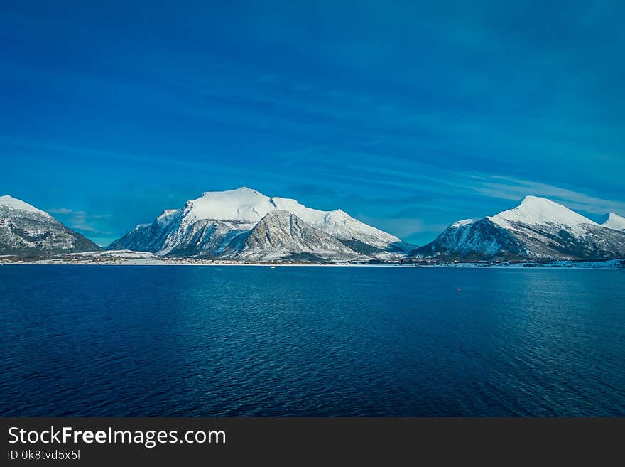 Outdoor view of mountain range in Norway. The beautiful mountain covered partial with snow in Hurtigruten region in Norway. Outdoor view of mountain range in Norway. The beautiful mountain covered partial with snow in Hurtigruten region in Norway.