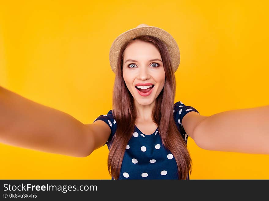 Self portrait of nice, amazing, pretty, positive, laughing, glad woman shooting selfie in two hands on front camera, having polka-dot outfit, isolated on yellow background