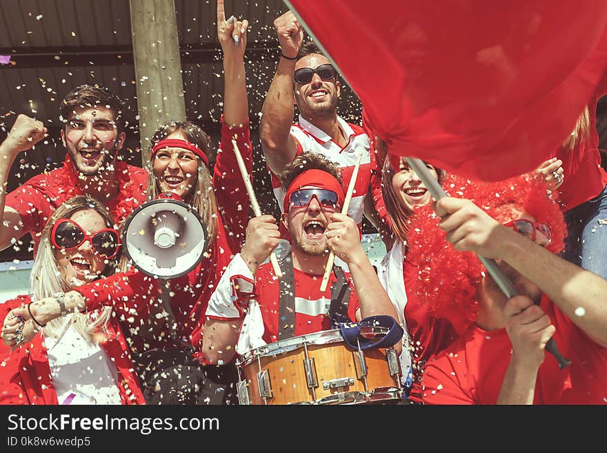 Group of fans dressed in red color watching a sports event