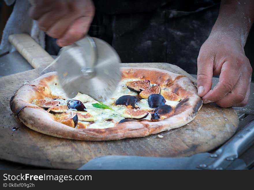 Vegetarian pizza with figs being cut with a cutting wheel. Vegetarian pizza with figs being cut with a cutting wheel