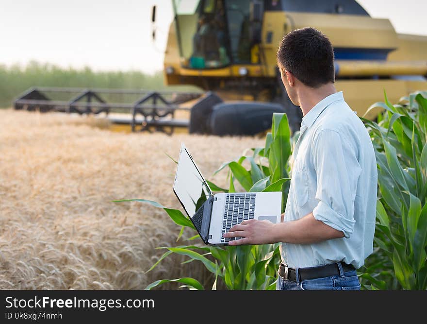 Engineer with laptop and combine harvester