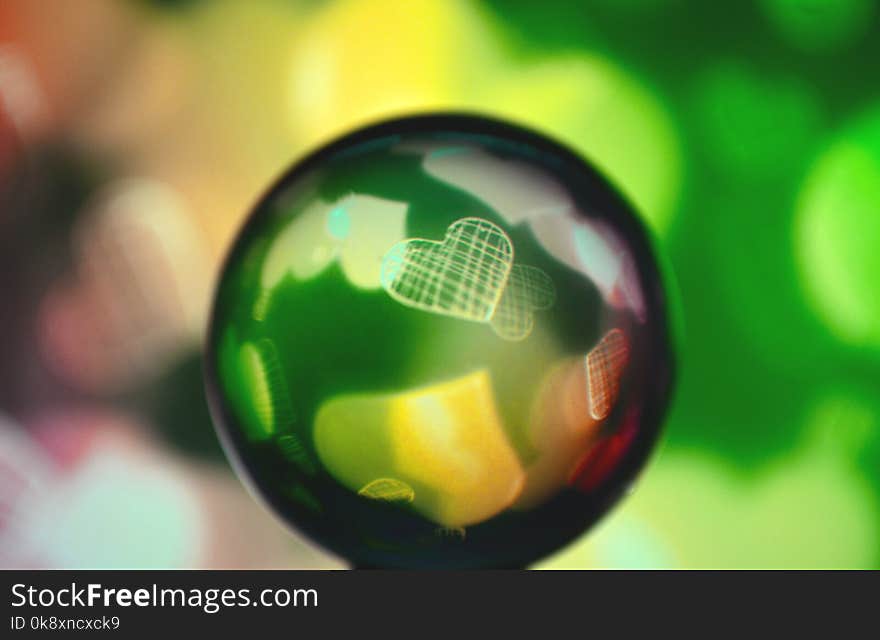 A colored glass sphere with a heart inside in yellow and green tones. A colored glass sphere with a heart inside in yellow and green tones