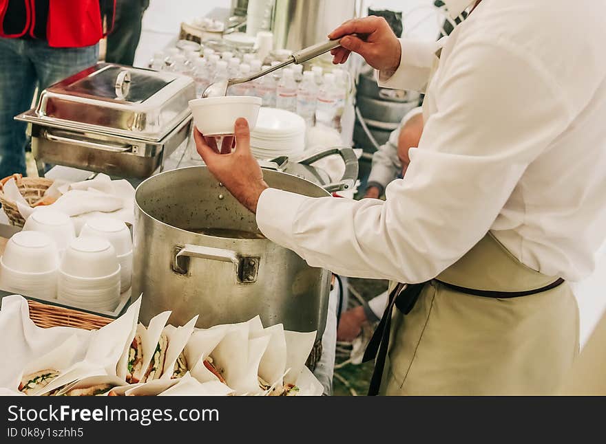 Food outside at an event with attendants in overalls and an apron. Food outside at an event with attendants in overalls and an apron