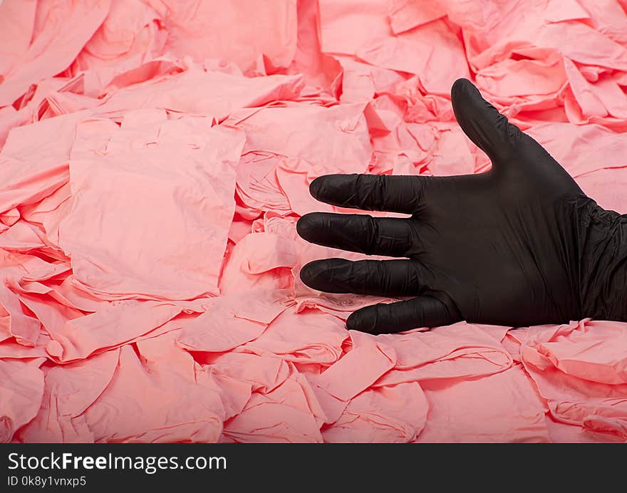 Hand in new black latex medical glove on background of a lot pink rubber gloves