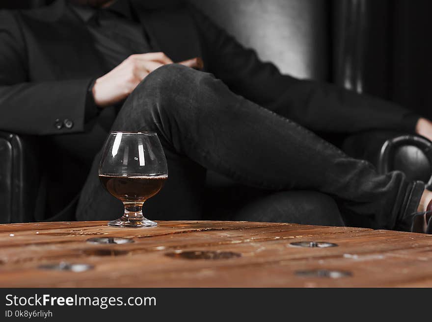 a glass for cognac on a wooden table on the background of a leather chair.