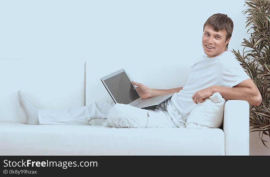 Very focused young man using laptop while sitting comfortably.