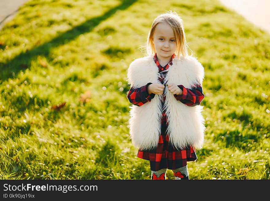 Young beautiful little stylish girl in a sunny autumn park