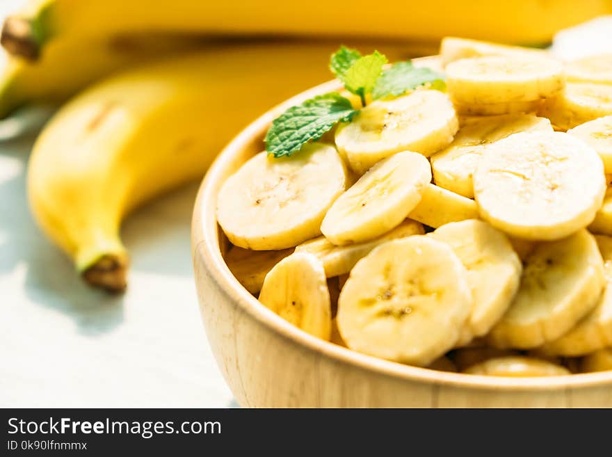 Raw yellow banana slices in wooden bowl